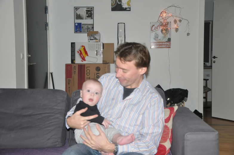 a man sitting on the couch holding his baby