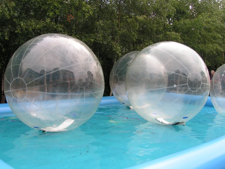 a group of three inflatable balloons floating on top of a pool