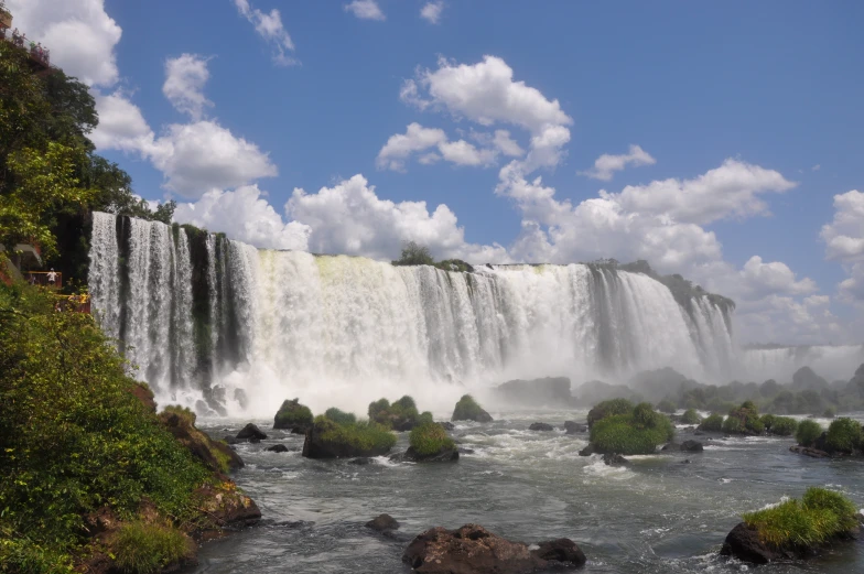 a waterfall surrounded by grass and water next to rocks