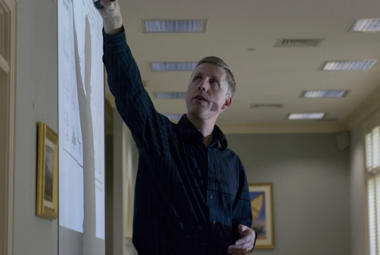 a man pointing on a whiteboard in a building