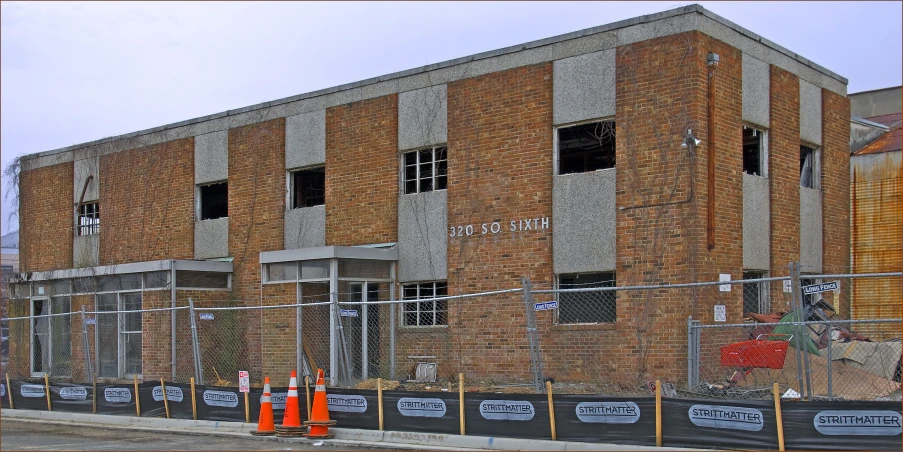 an empty building on the corner with orange barricade poles