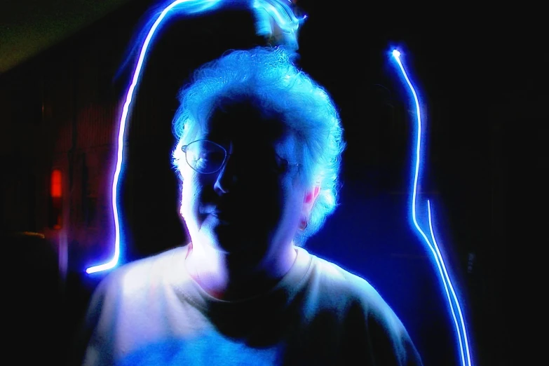 a person wearing glasses and standing in front of blue light