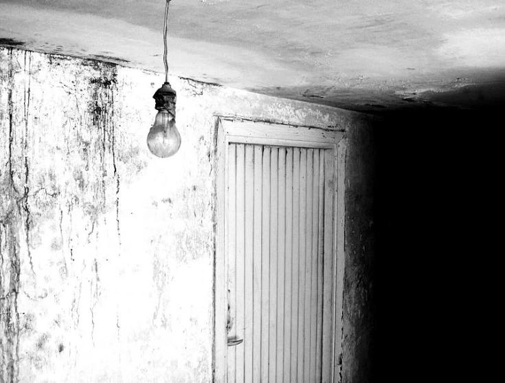 an old hanging light in a room with door and light bulb