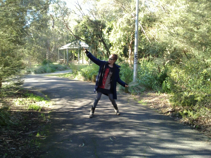 a woman is walking on the road with trees in the background