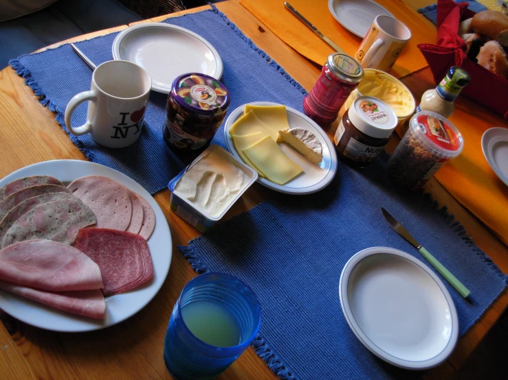 a table topped with meat and cheese plates and cups