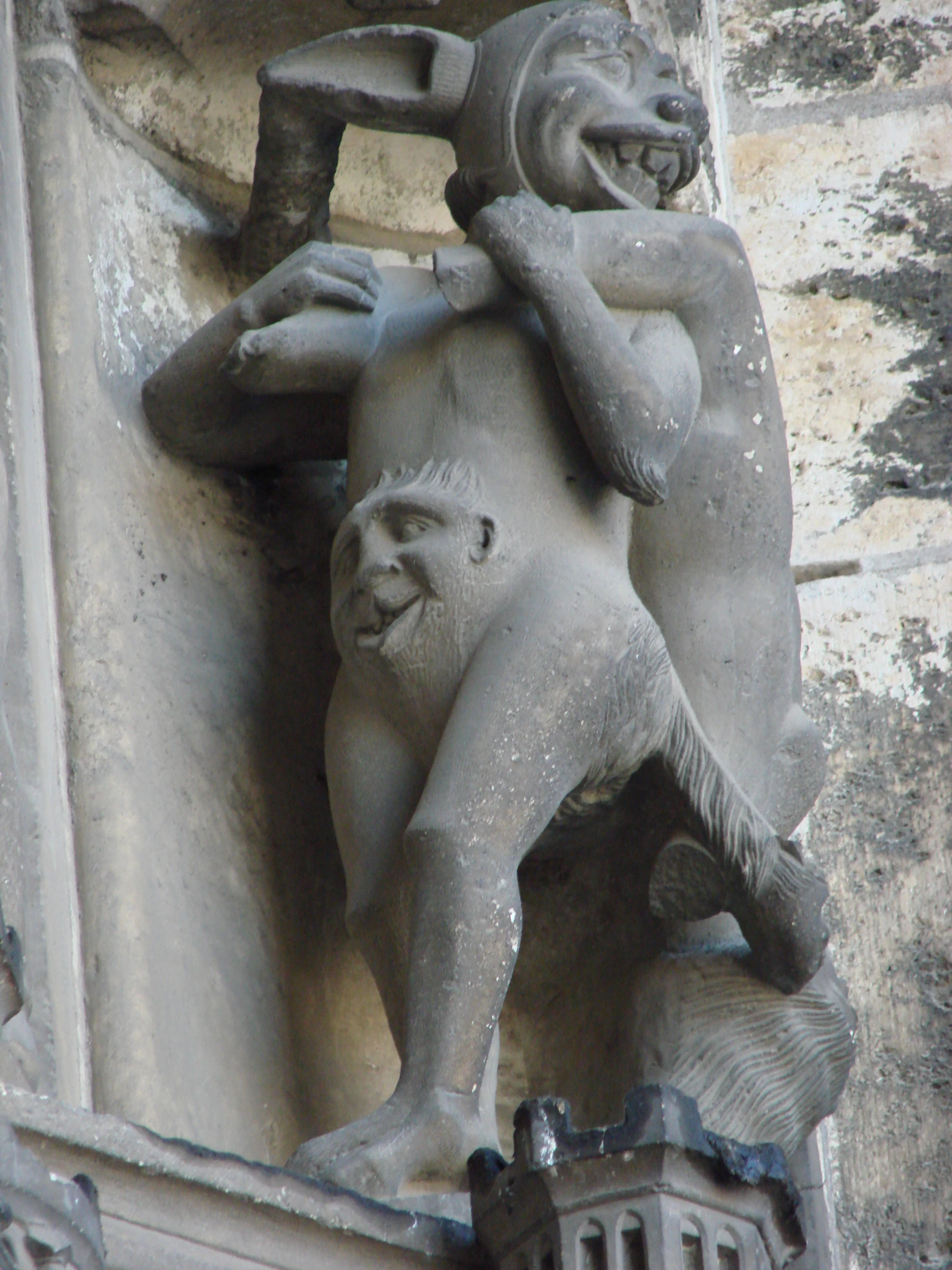 statue of devil in front of building with balcony and columns