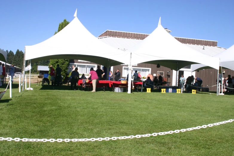 a large group of people that are sitting under white tents