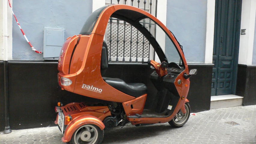 an orange and black small passenger vehicle on the side of the street