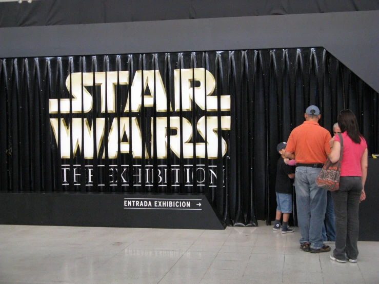 a group of people standing outside of a star wars exhibit