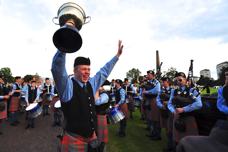 the man in the kilt is raising his arms