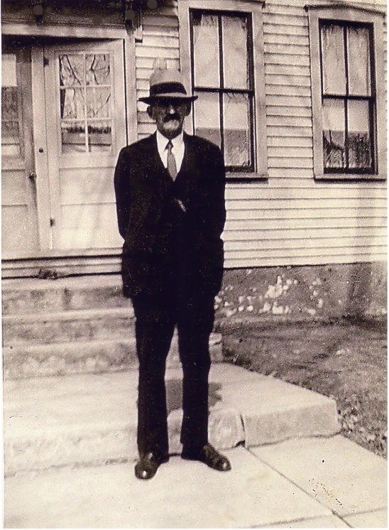 man standing outside the entrance to a home in black and white