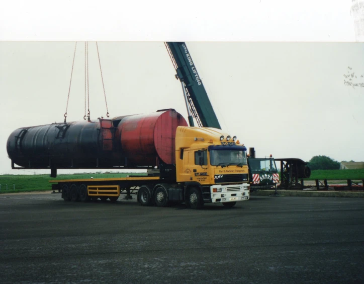 a yellow truck being lifted by a crane