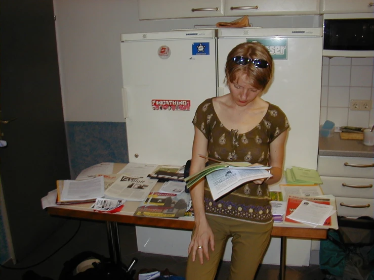 a lady standing with her feet up and reading a paper