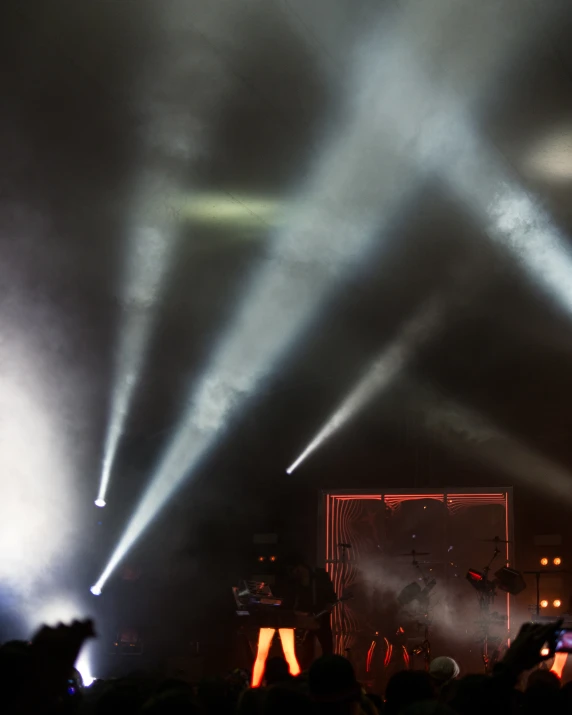 a crowd watches as stage lighting shine overhead