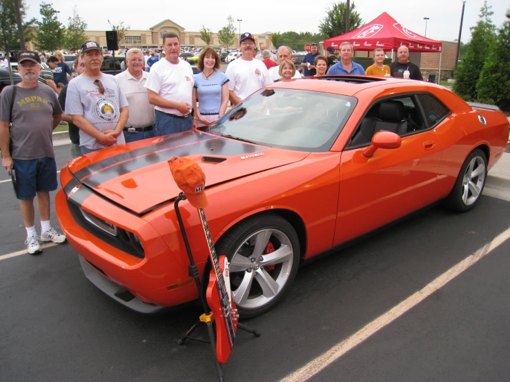 some people standing around a red sport car