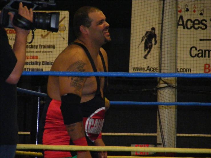 a man with tattoos walking around in a boxing ring