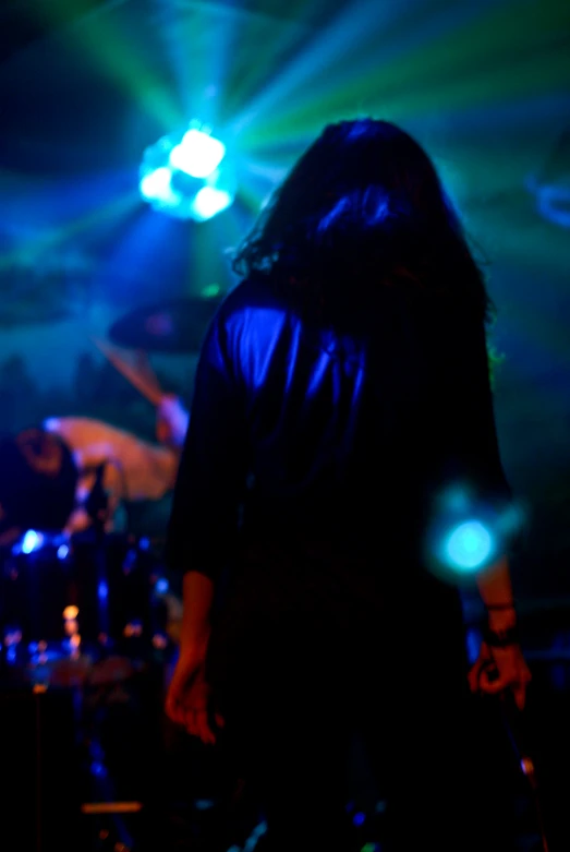 bandleader with long hair and a microphone, on stage