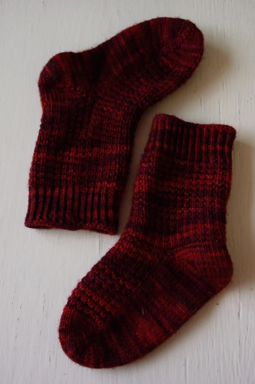 two pairs of red socks are laying on a white surface