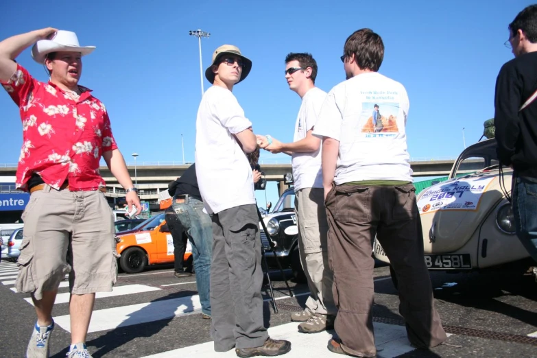 four men standing in front of a parked car
