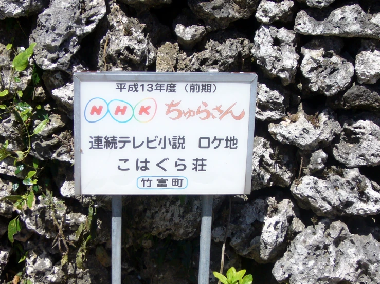 a sign on the side of a mountain pointing directions in two languages