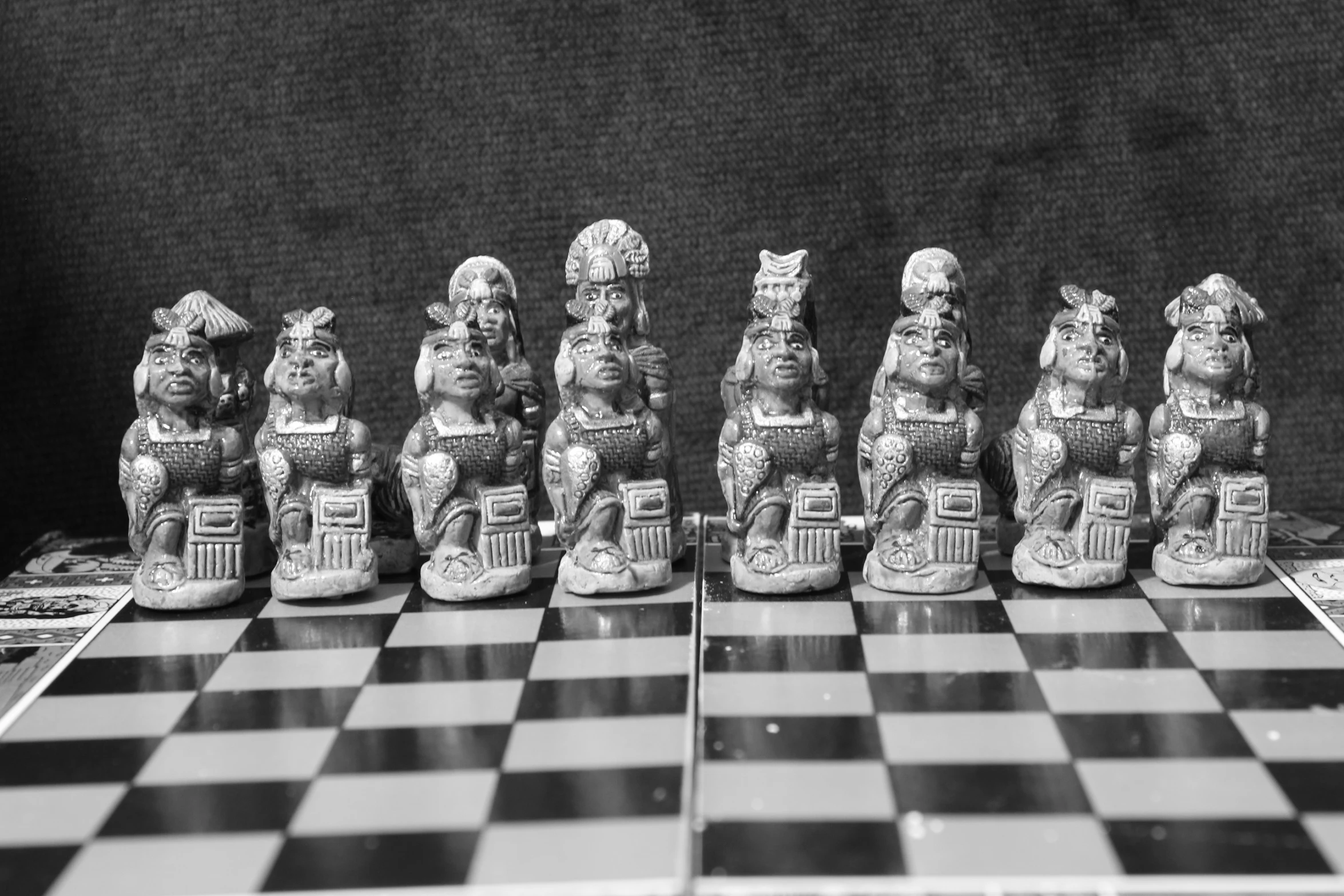 some statues are sitting on a chess board