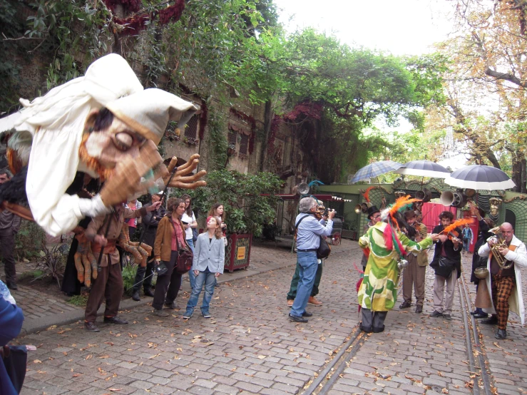 several people are standing on a sidewalk and many are holding umbrellas