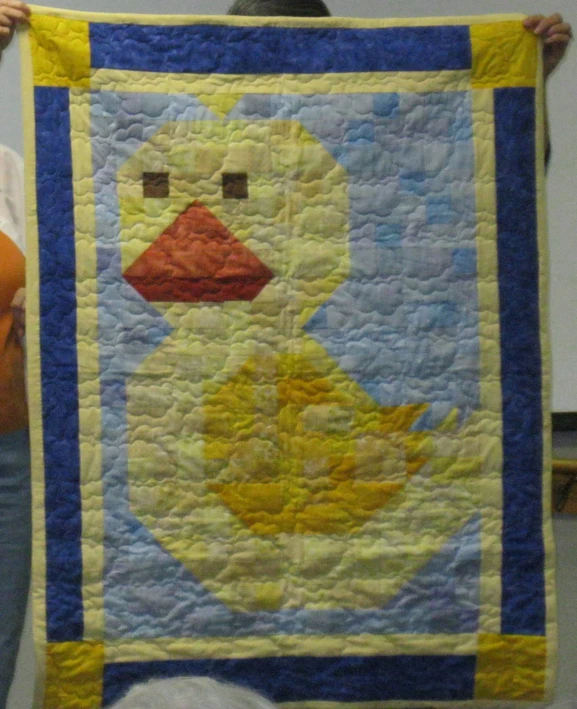 a woman is holding up her hand made quilt