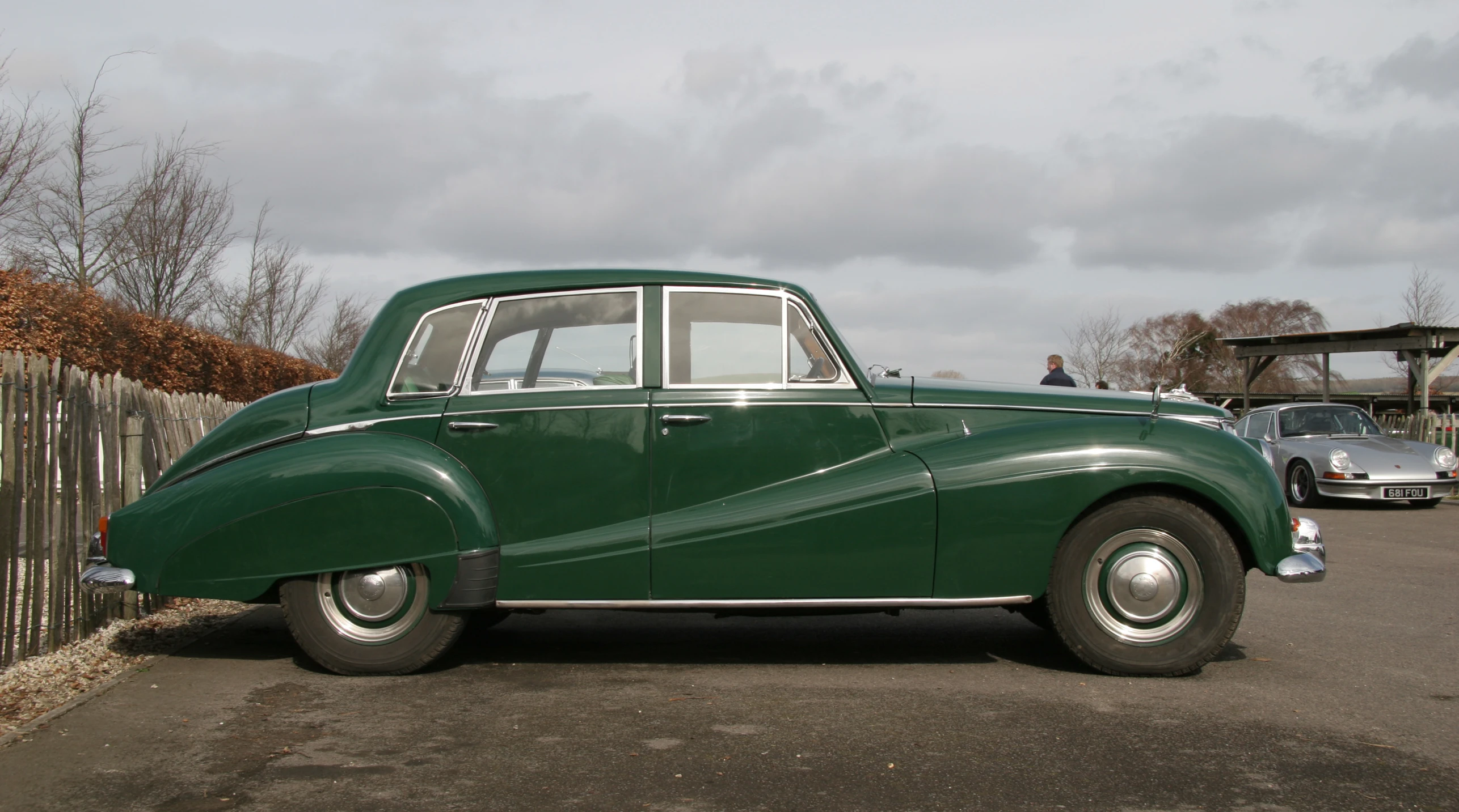 an old fashioned green car parked next to a fence