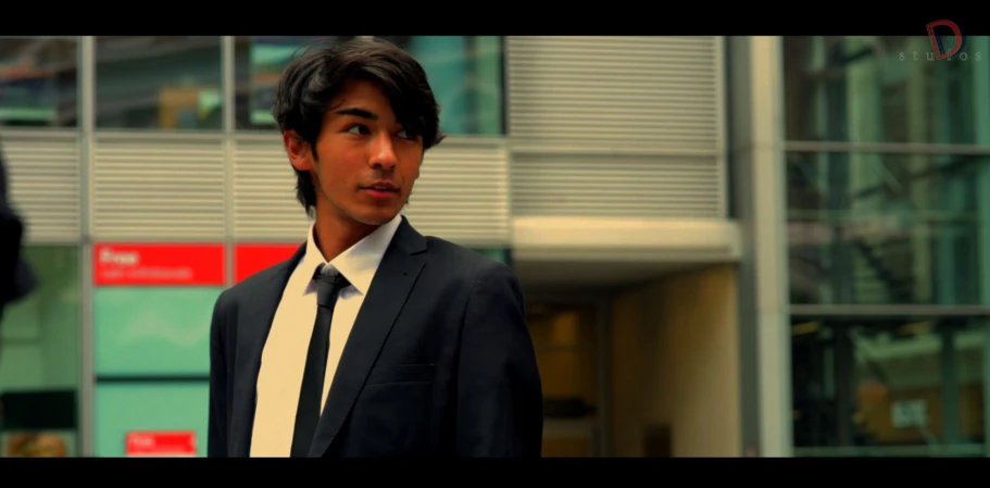 a man in suit and tie next to a building