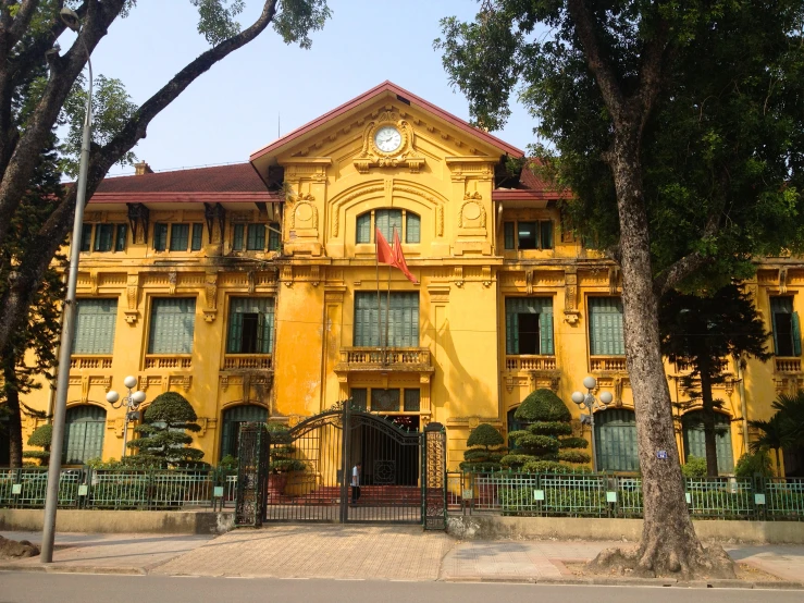 a building has yellow paint and green trees