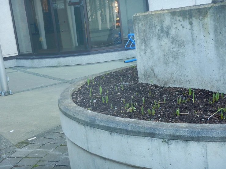 a large concrete planter on a sidewalk in front of a window