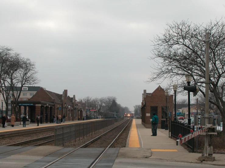 train tracks at a small train station on a cloudy day