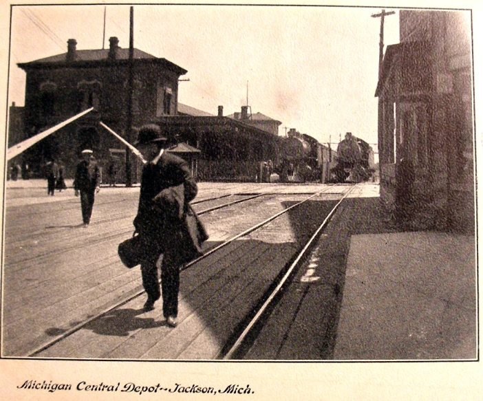 a black and white po of a train station with people walking by