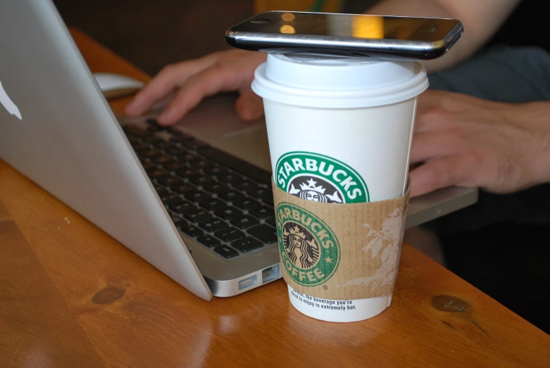 a starbucks cup sitting on top of a laptop computer