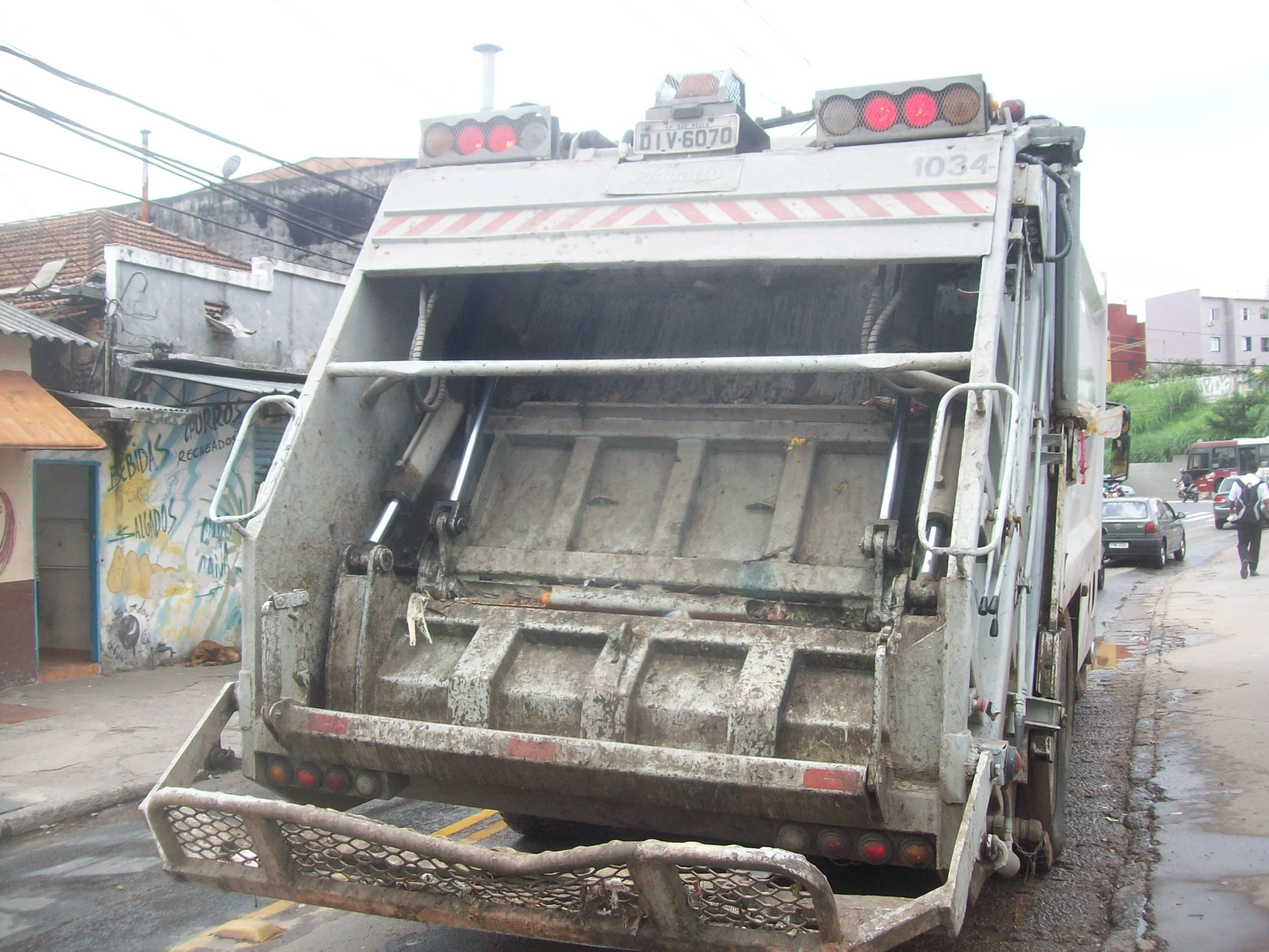 a garbage truck stopped at a curb with it's doors open