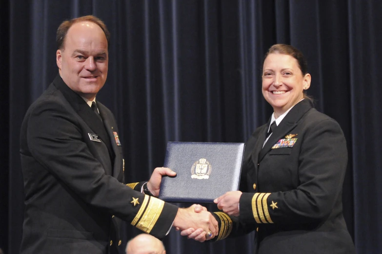 two people shaking hands in uniform and wearing medals