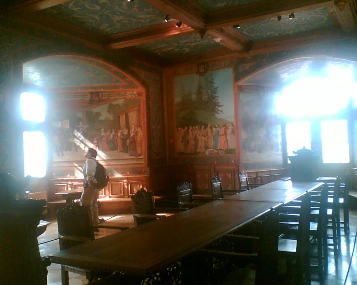 a large wooden table is near three windows