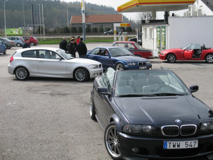 two men stand beside a row of parked bmw cars
