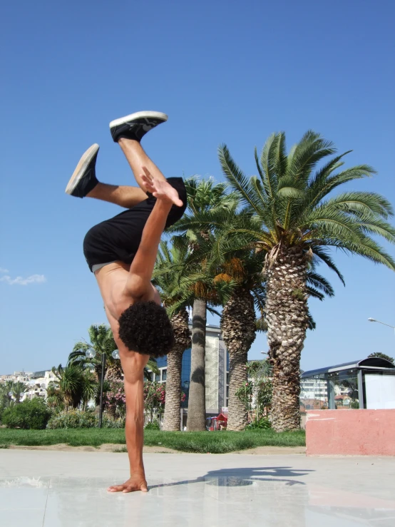 a woman in shorts doing a handstand on top of one hand