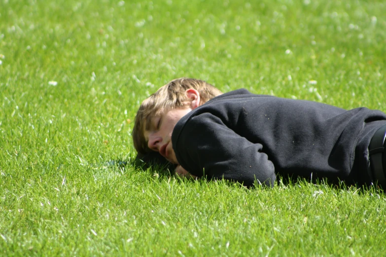 a little  laying in the grass with his eyes closed