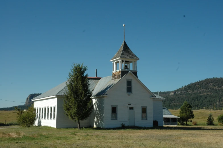 an old white church in the country, near a hill