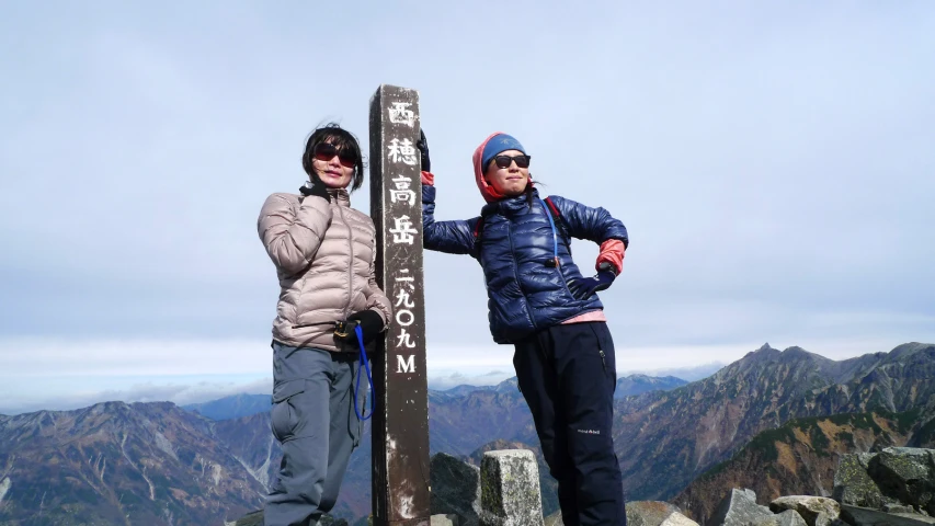 two young men are standing on the summit of a mountain