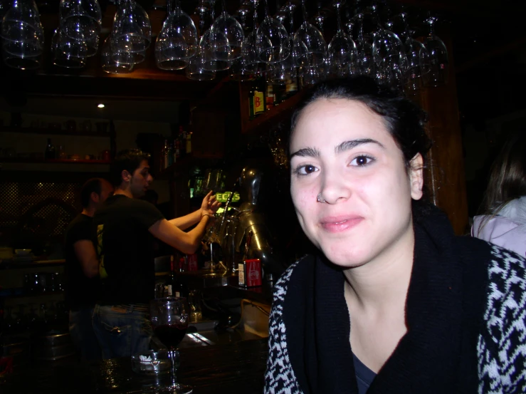 a lady wearing a scarf poses for the camera at a bar