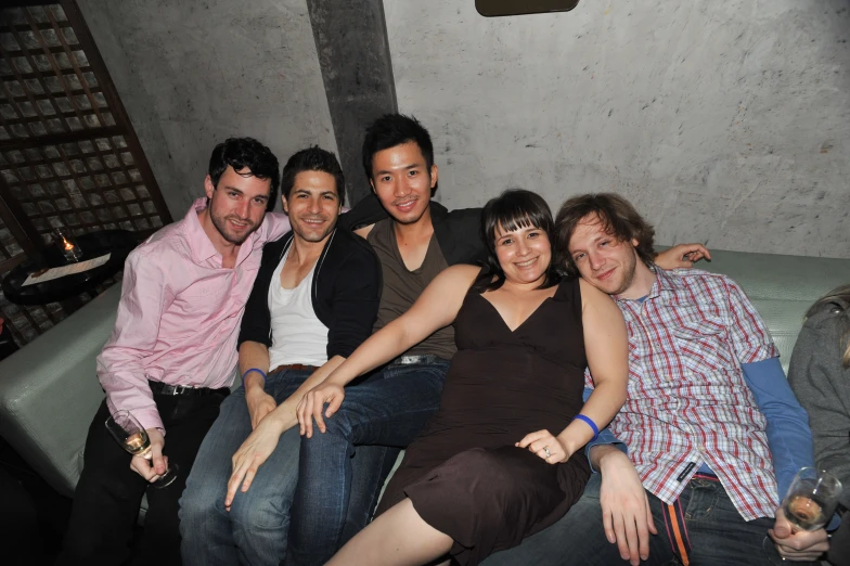 four people posing for a picture while sitting on a couch