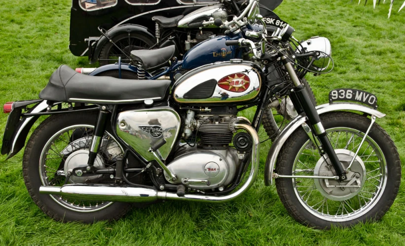 a silver motorcycle and a black one are parked in grass