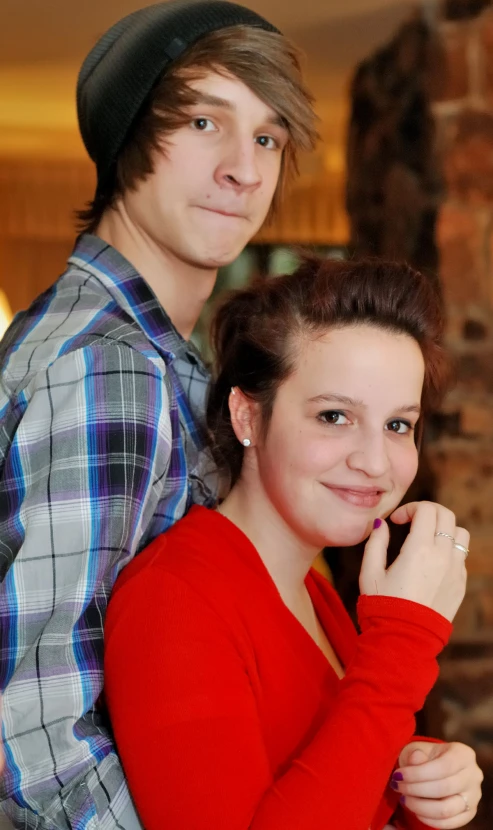 two people are posing for a picture with a brick wall