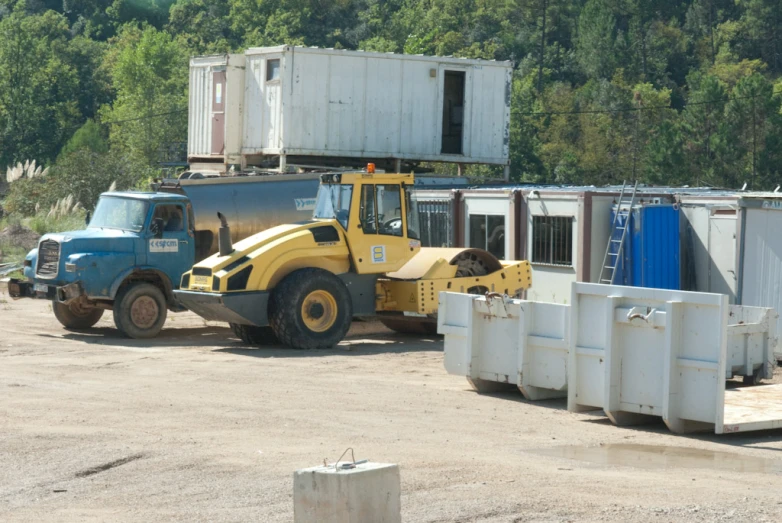 a bulldozer parked next to several shipping containers