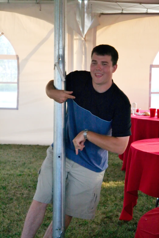 a man leaning against a pole smiling and posing