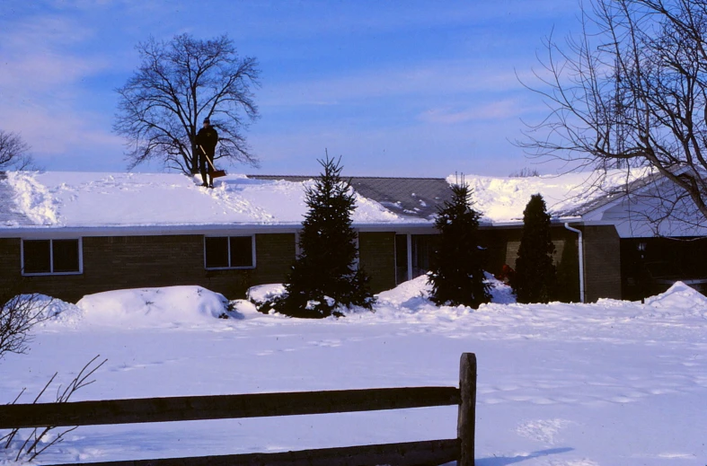 a fence next to a brown building in a snowy field