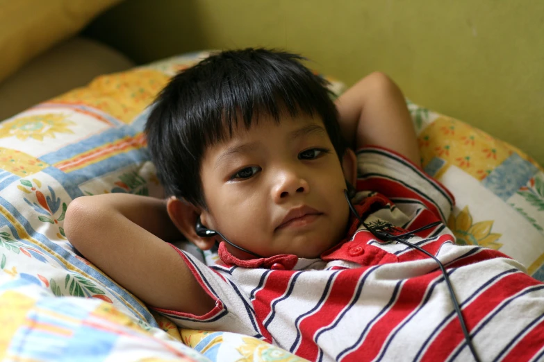 a young child in a striped shirt laying in bed